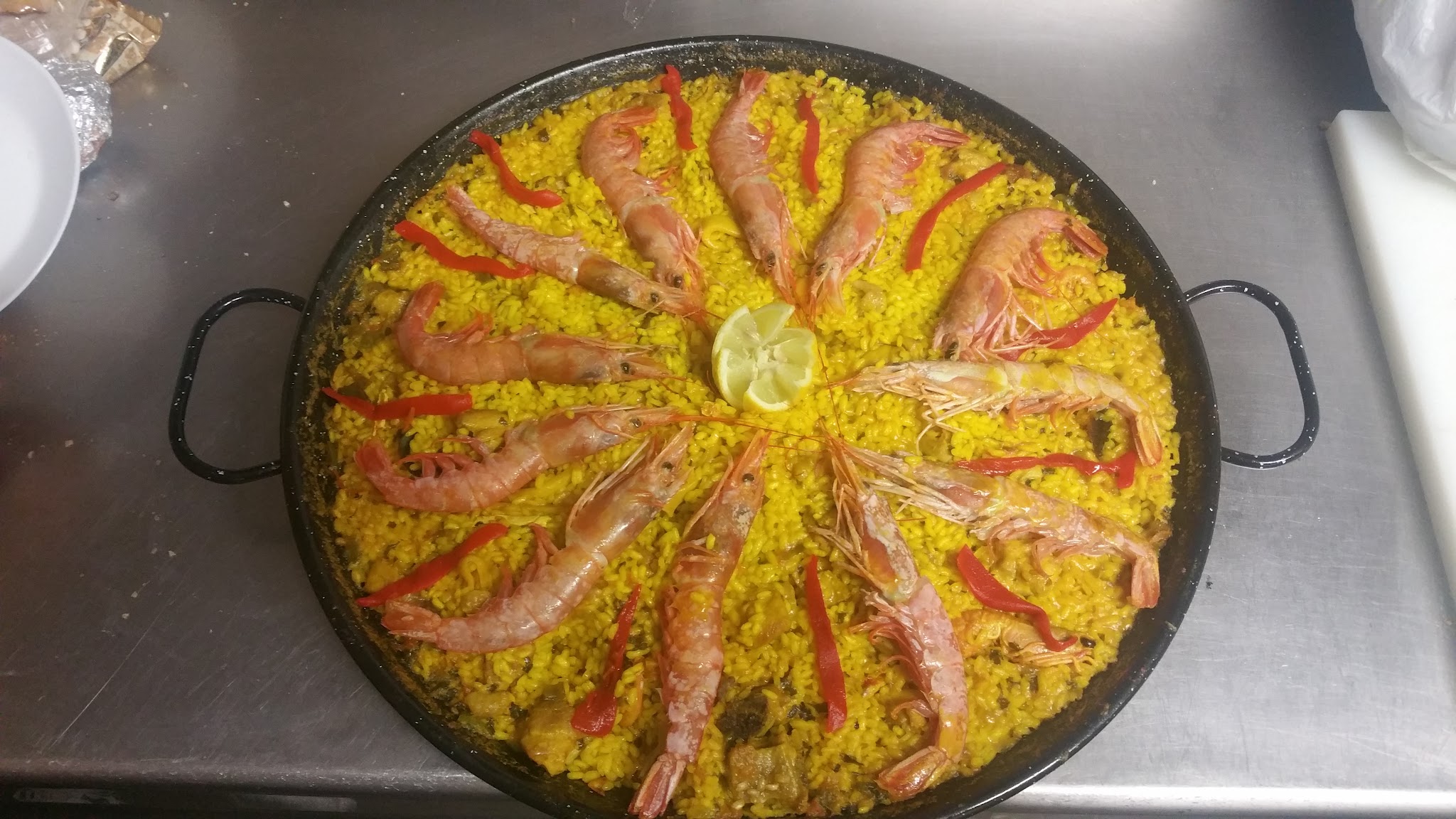 Paella de marisco recién hecha con langostinos y pimiento rojo en el Mesón The River